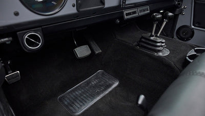 Pedals and floor area of Classic Ford Bronco interior showing black carpeting and shifter levers