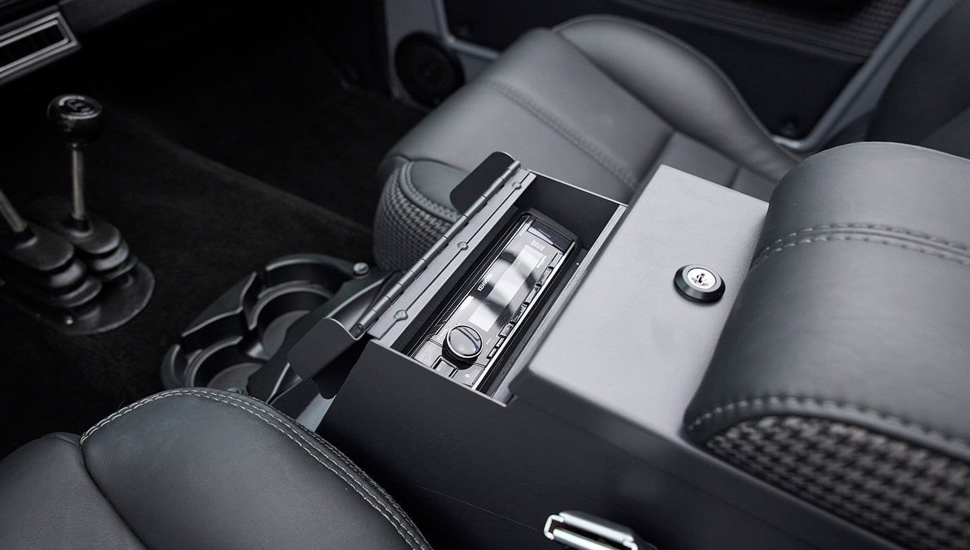 Black center console with open storage compartment and stereo controls inside, black leather seats nearby