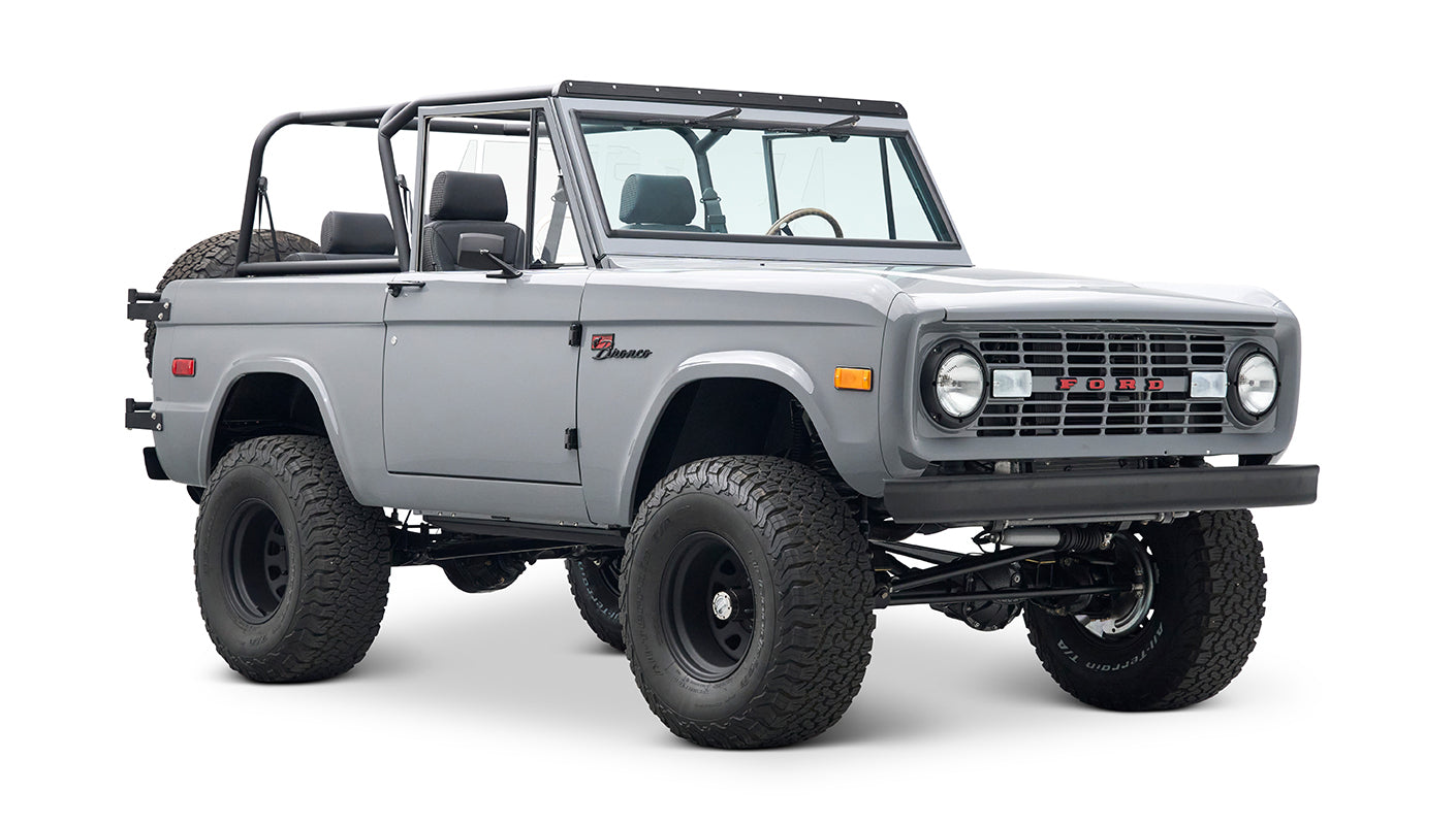 Three-quarter front view of a Classic Ford Bronco in gray with black wheels and a roll cage