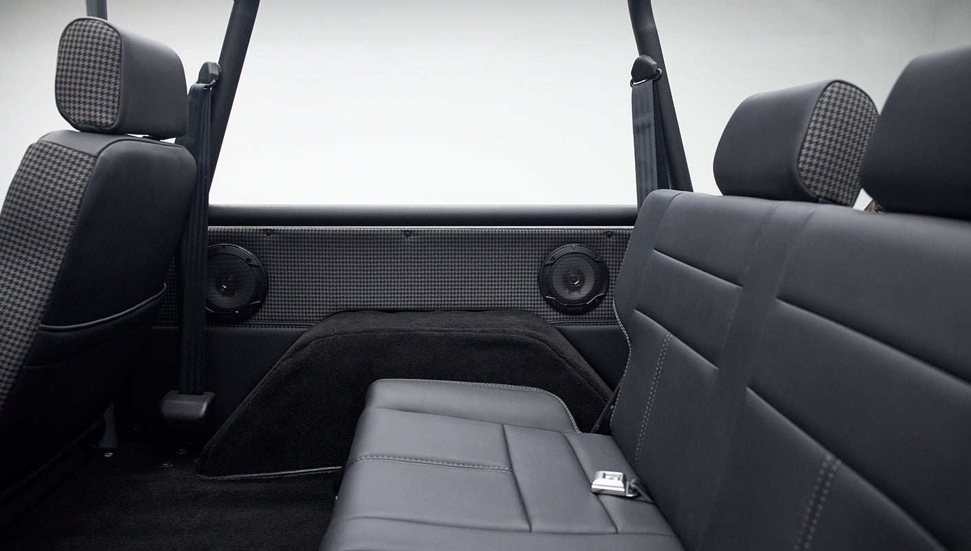 Side view of classic Ford Bronco rear black leather seat with houndstooth pattern on door panel and two speakers
