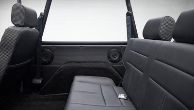 Side view of classic Ford Bronco rear black leather seat with houndstooth pattern on door panel and two speakers
