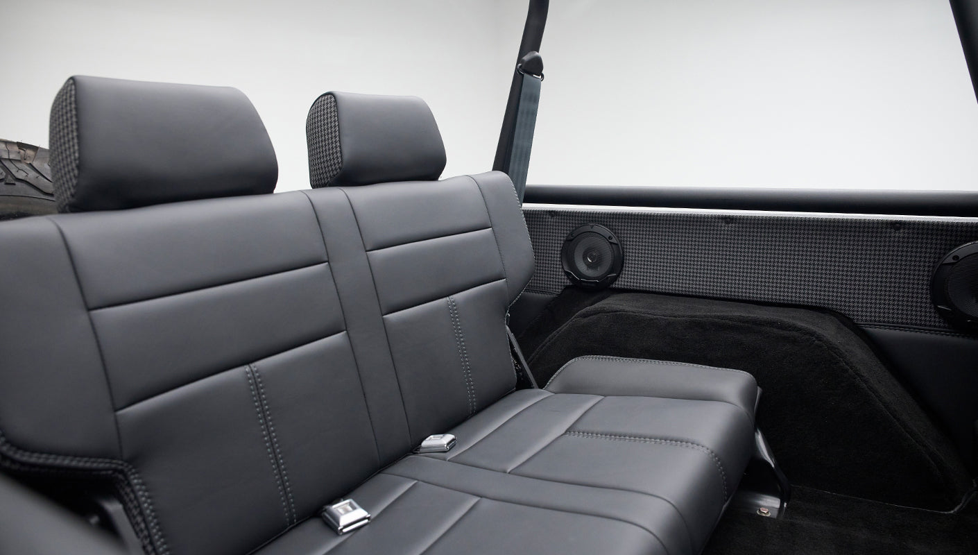 Close-up of chrome seat belt buckle on black leather rear bench seat inside Classic Ford Bronco