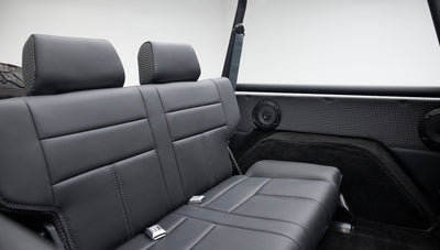 Close-up of chrome seat belt buckle on black leather rear bench seat inside Classic Ford Bronco