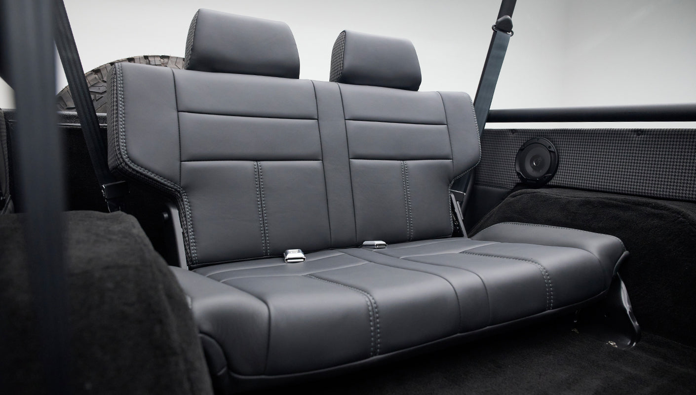 Rear black leather bench seat viewed from side, showing seat contours and stitching details