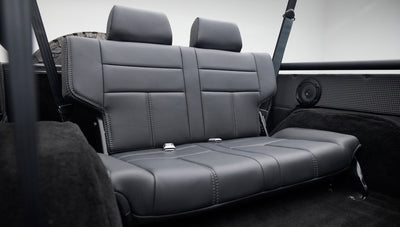 Rear black leather bench seat viewed from side, showing seat contours and stitching details