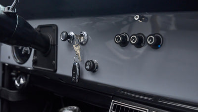 Dashboard section with ignition keys in switch, round control knobs, and gray painted surface inside Classic Ford Bronco