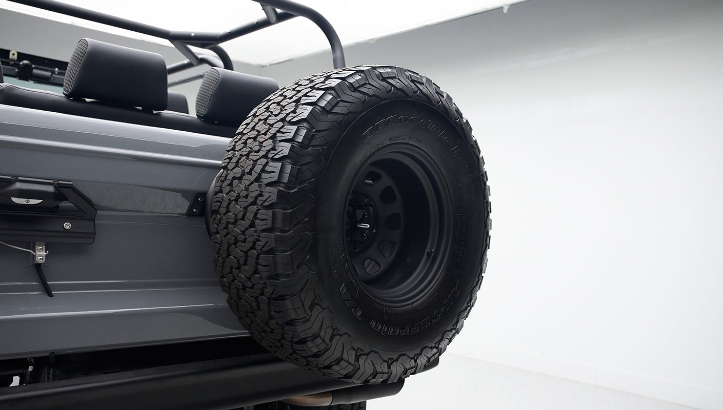 Close-up of spare tire mounted on rear side of gray Classic Ford Bronco with black seats.