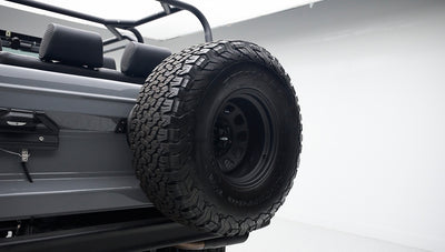 Close-up of spare tire mounted on rear side of gray Classic Ford Bronco with black seats.