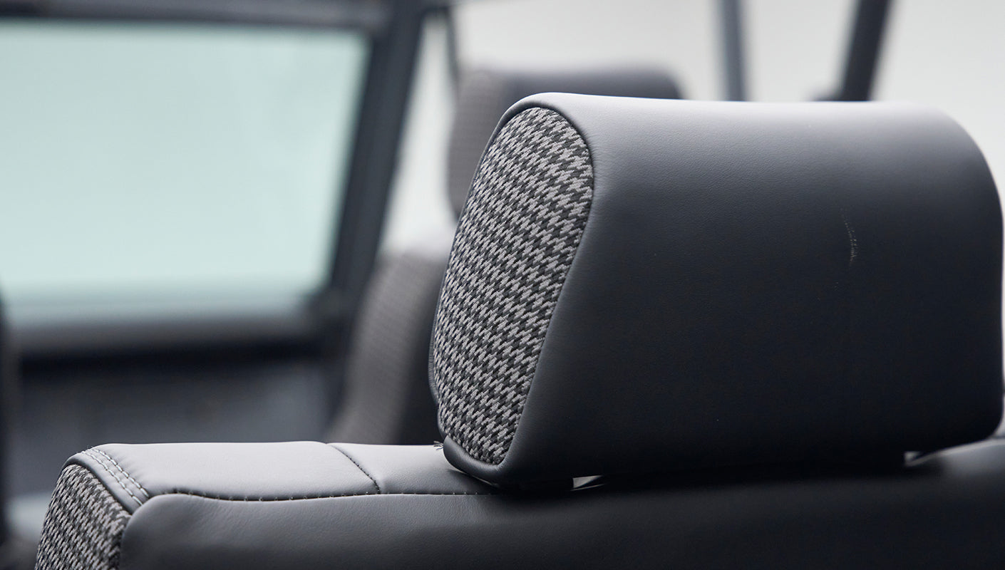 Close-up of Classic Ford Bronco interior black headrest with gray houndstooth fabric insert.