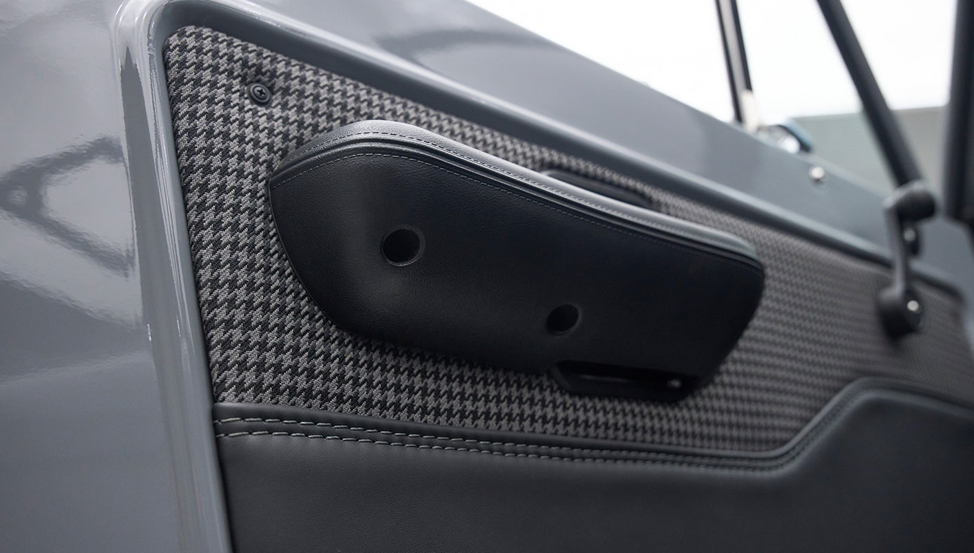 Black leather armrest on gray Classic Ford Bronco door panel with gray houndstooth fabric.