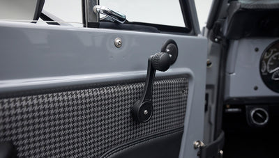 Manual window crank on gray Classic Ford Bronco door panel with black and houndstooth fabric.