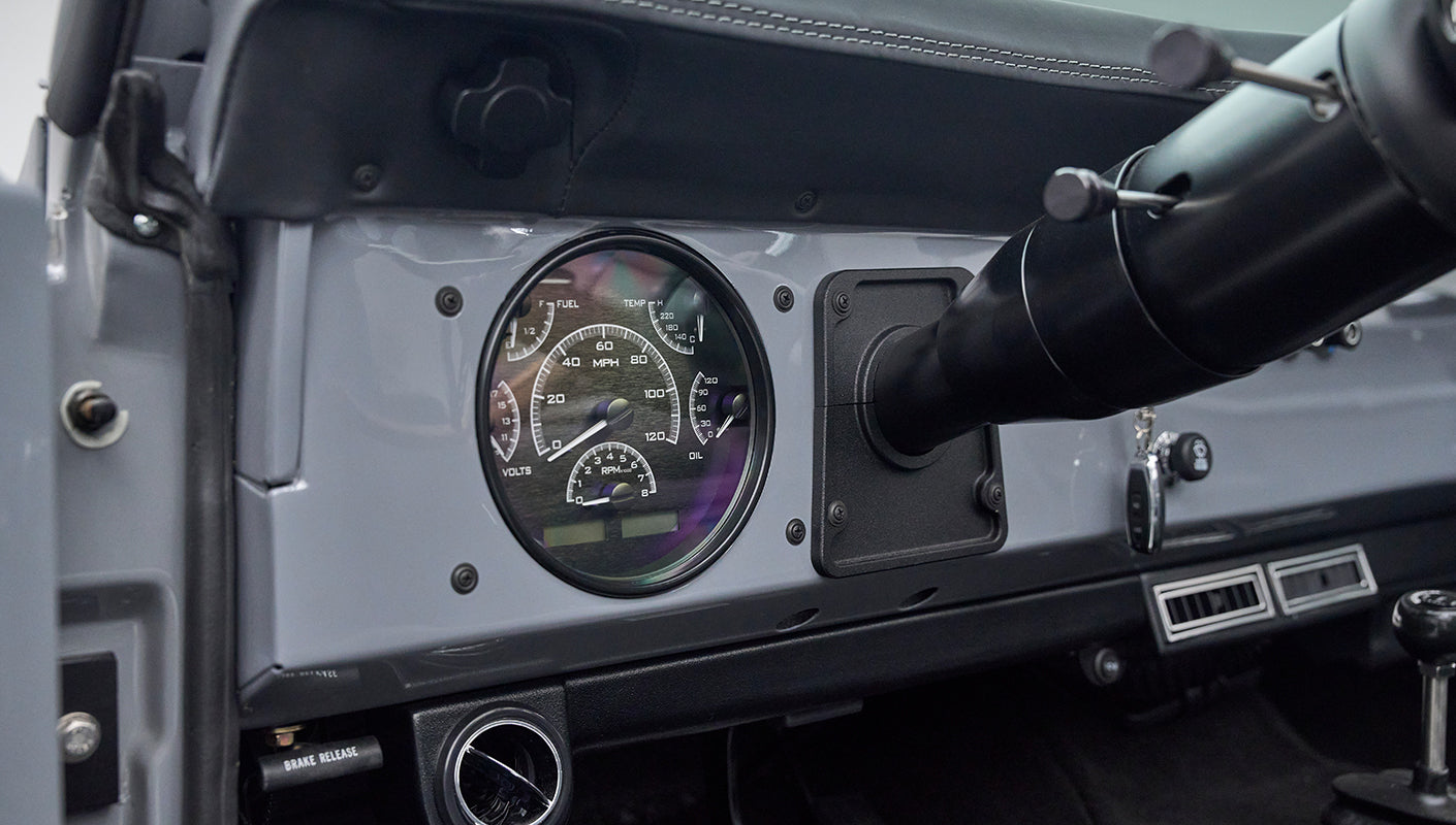 Classic Ford Bronco instrument cluster with round gauges including speedometer and tachometer.