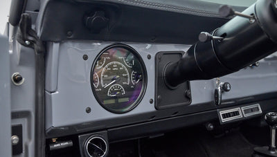 Classic Ford Bronco instrument cluster with round gauges including speedometer and tachometer.