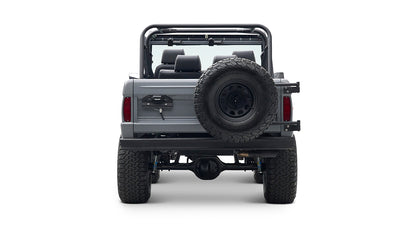 Rear view of a Classic Ford Bronco in gray with spare tire mounted on back, large tires, and roll cage