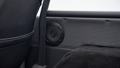 Kenwood speaker mounted on gray houndstooth patterned panel with seatbelt strap inside Classic Ford Bronco