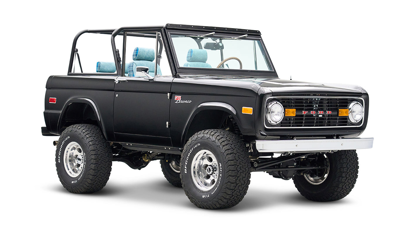 Side angle of black Classic Ford Bronco with lifted suspension and blue plaid interior visible