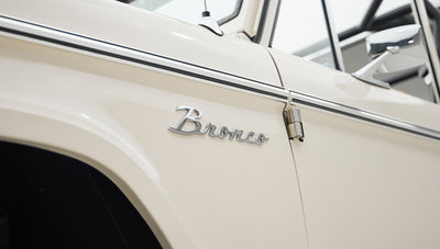 Side view of Classic Ford Bronco showing beige paint and chrome Bronco emblem