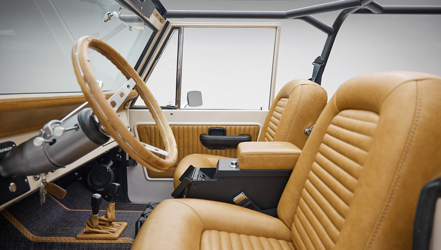 Driver side interior of Classic Ford Bronco with tan leather seats and white dashboard