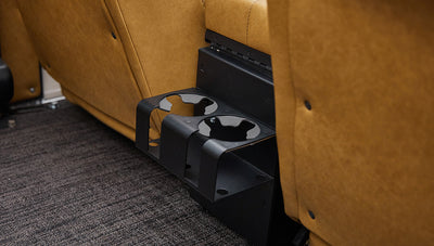 Black rear cup holders attached under tan leather seat inside vehicle