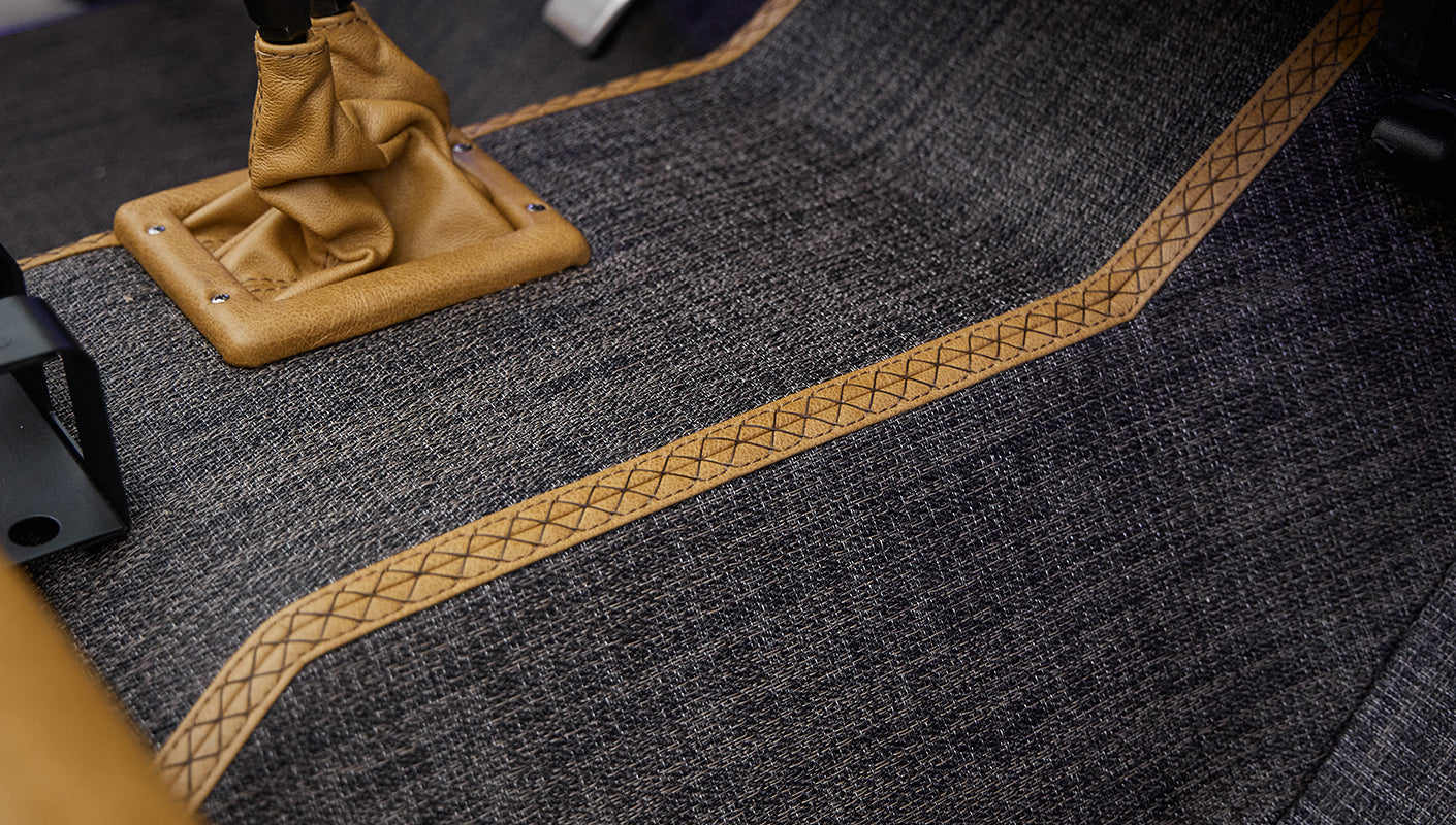 Tan leather gear shift boot on gray carpet with tan stitched trim