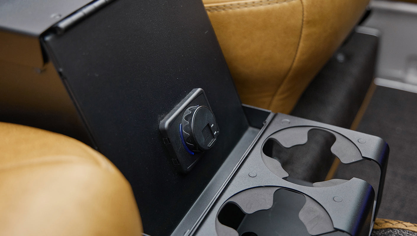 Black rear cup holders and power outlet on center console with tan leather seats