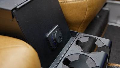 Black rear cup holders and power outlet on center console with tan leather seats