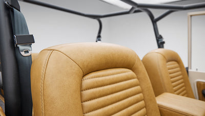 Close-up of tan leather bucket seats with black roll bar behind