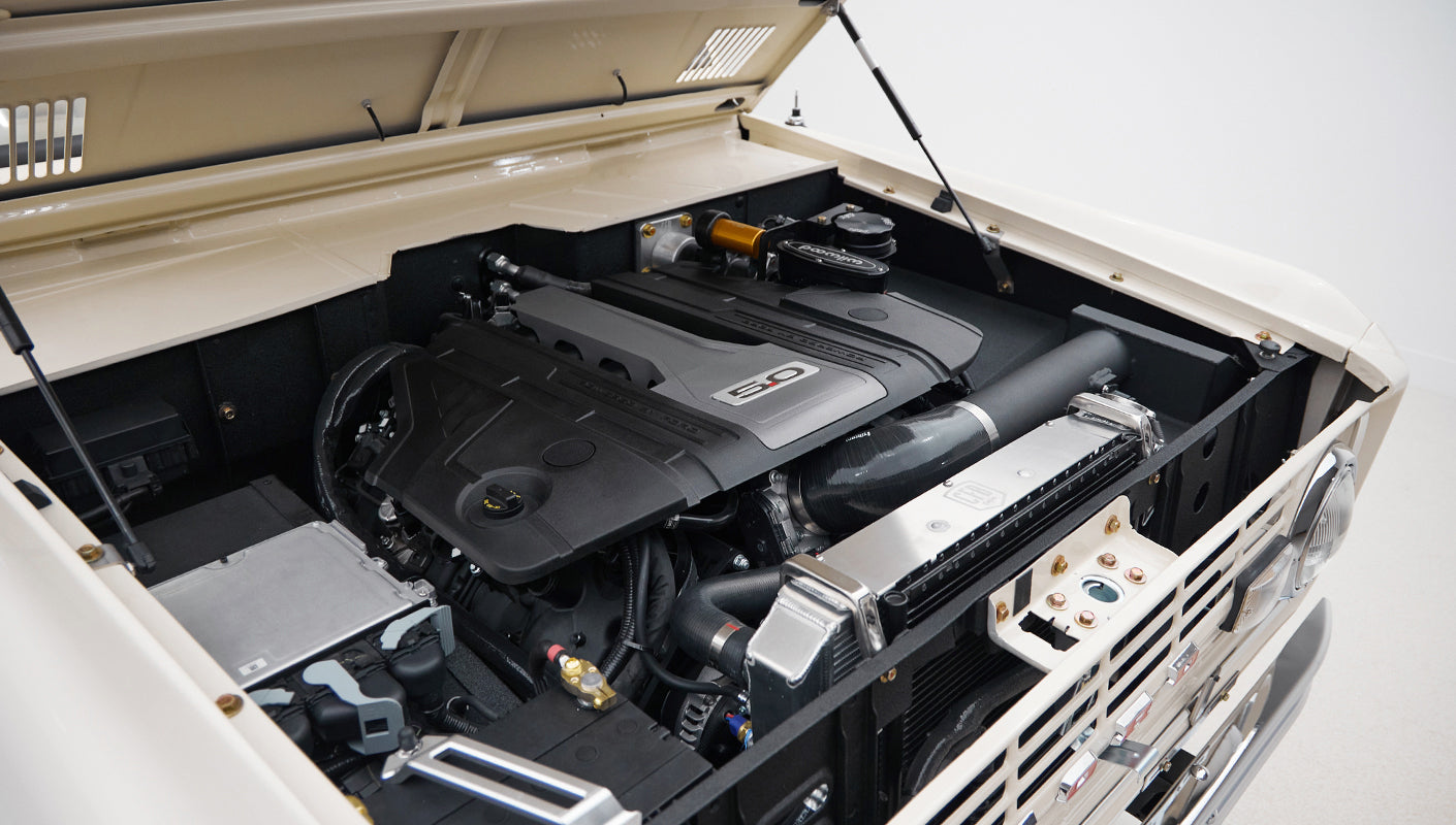 Engine bay with 5.0 engine cover and various mechanical components