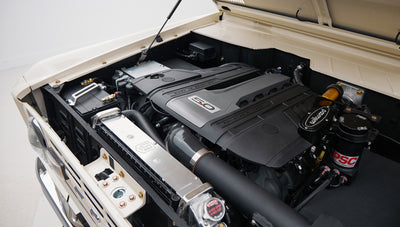 Close-up of Classic Ford Bronco engine compartment showing black engine cover with 5.0 label