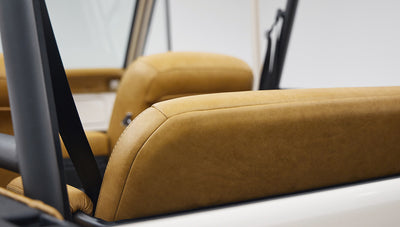 Tan leather seat backs inside Classic Ford Bronco with black roll cage