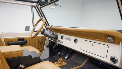 Interior of vehicle with tan leather seats, steering wheel, and beige dashboard with controls and key chain