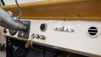 Close-up of beige dashboard with chrome air vents, knobs, and attached keys with leather keychain