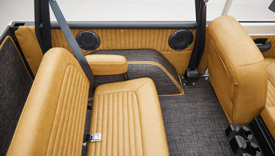 Interior rear side seating area with tan leather seats and gray carpet with striped pattern