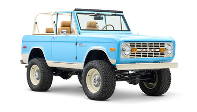 Three-quarter front view of Classic Ford Bronco in bright blue with beige trim and large tires