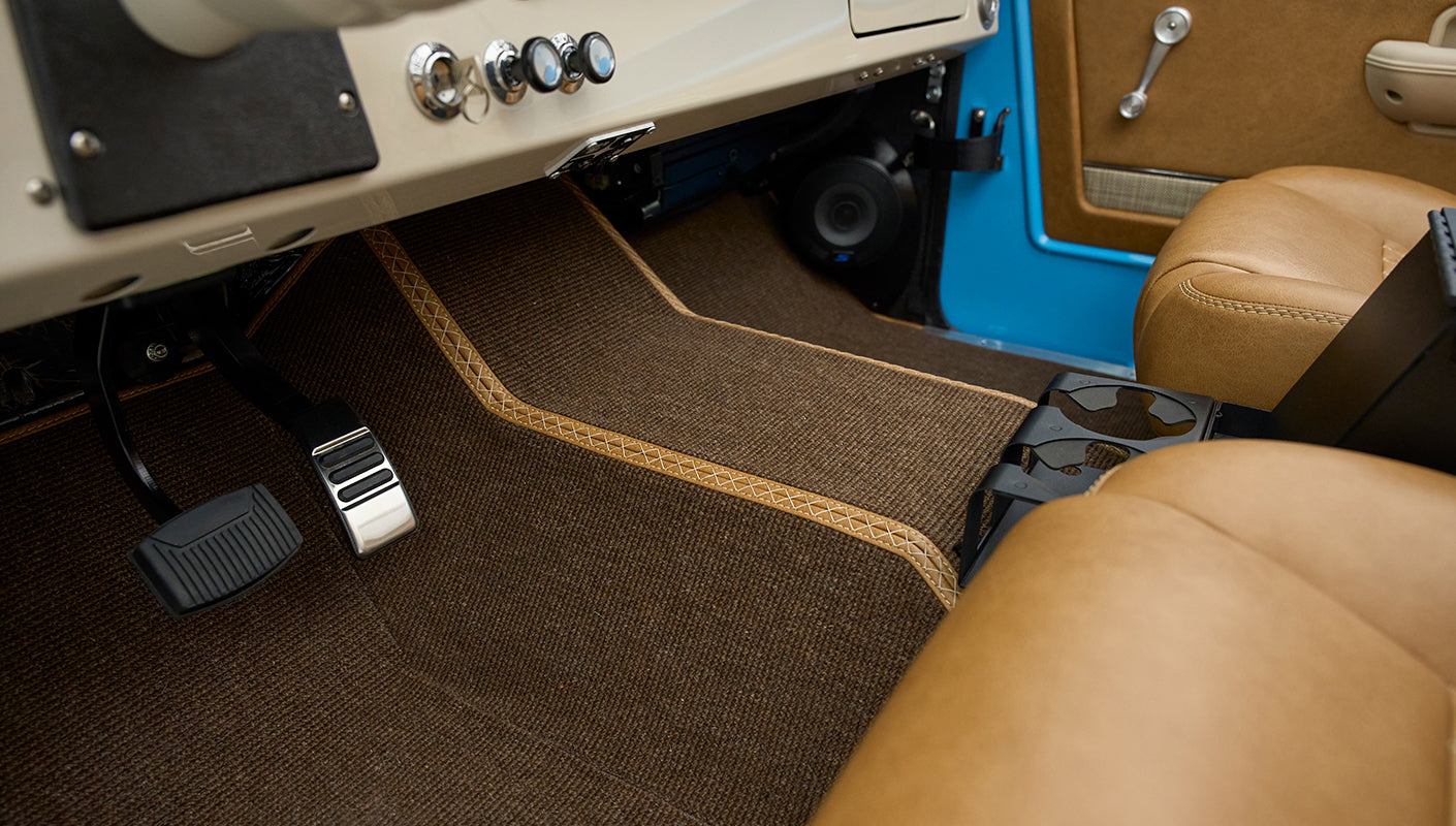 Driver side footwell area in Classic Ford Bronco with brown carpet and tan seats
