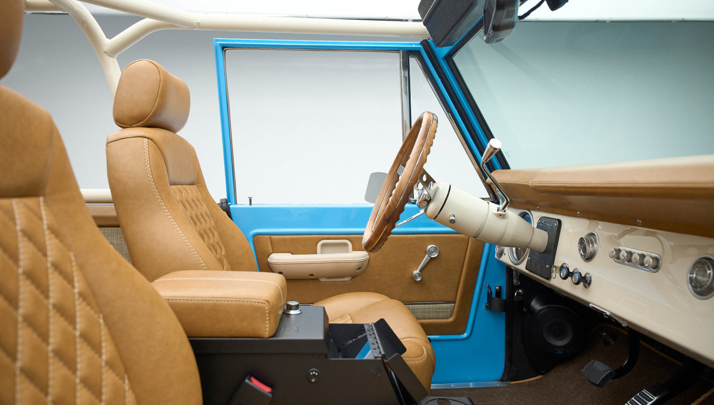Classic Ford Bronco interior side view featuring brown leather front seats and steering wheel
