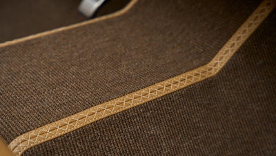 Close detail of brown carpet floor mat with stitched leather border inside classic Ford Bronco