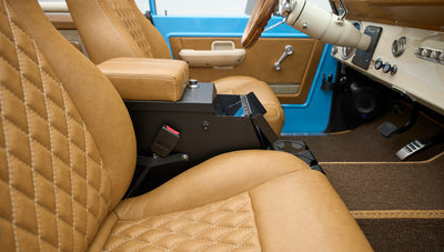 View of front bucket seats and interior console with open compartment in classic Ford Bronco