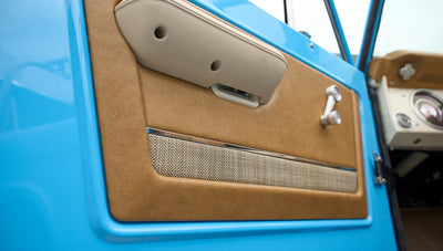 Close-up of tan and gray door panel inside Classic Ford Bronco with blue exterior