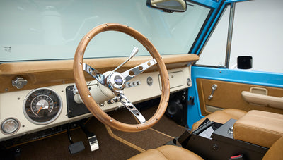 Wooden steering wheel and dashboard of Classic Ford Bronco with tan interior