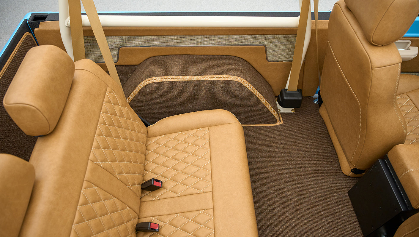 Rear interior seating area of Classic Ford Bronco with tan leather seats and seat belts
