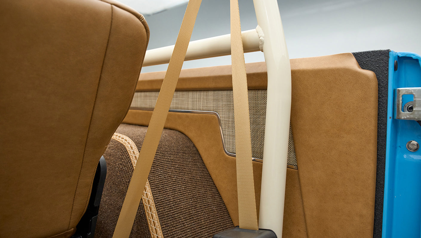 Interior side panel and roll cage of Classic Ford Bronco with tan upholstery and fabric accents