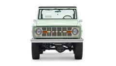 Front view of a mint green Classic Ford Bronco with white interior and black roof