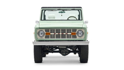Front view of a mint green Classic Ford Bronco with white interior and black roof