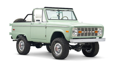 Classic Ford Bronco in pale green with white interior and black roll bar, three quarter front view slightly tilted