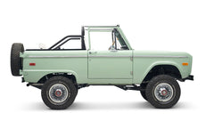 Classic Ford Bronco in pale green with white interior and black roll bar, side view without doors