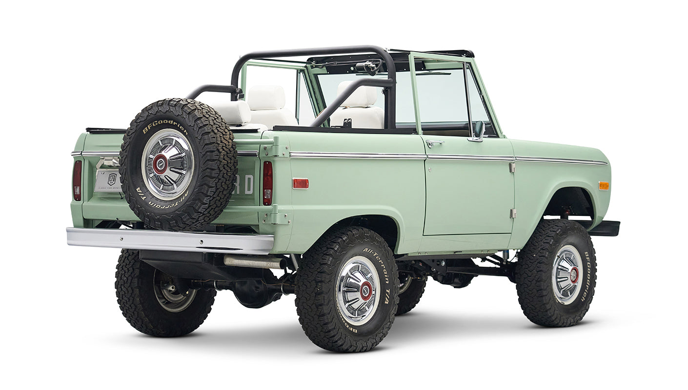 Classic Ford Bronco in pale green with white interior and black roll bar, three quarter rear view from opposite angle