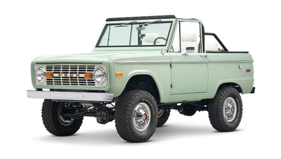 Classic Ford Bronco in pale green with white interior and black roll bar, three quarter front view angled