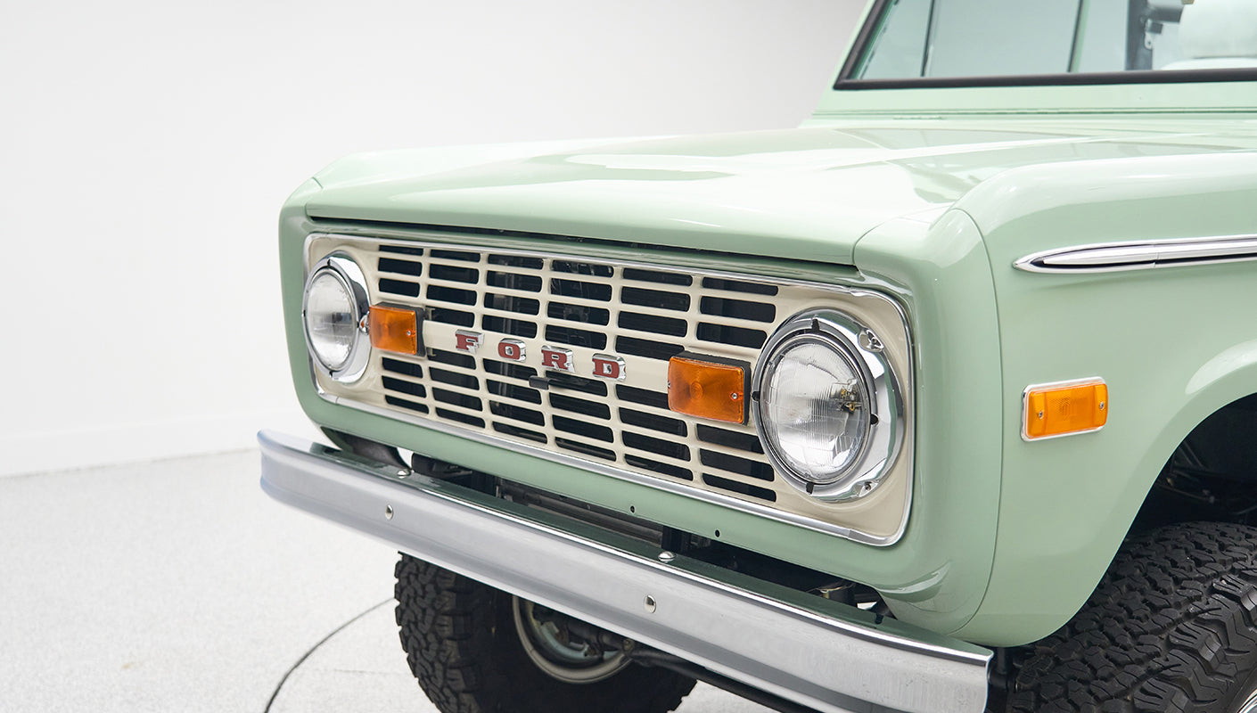 Close-up of front grille and headlights on mint green Classic Ford Bronco