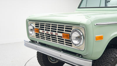 Close-up of front grille and headlights on mint green Classic Ford Bronco